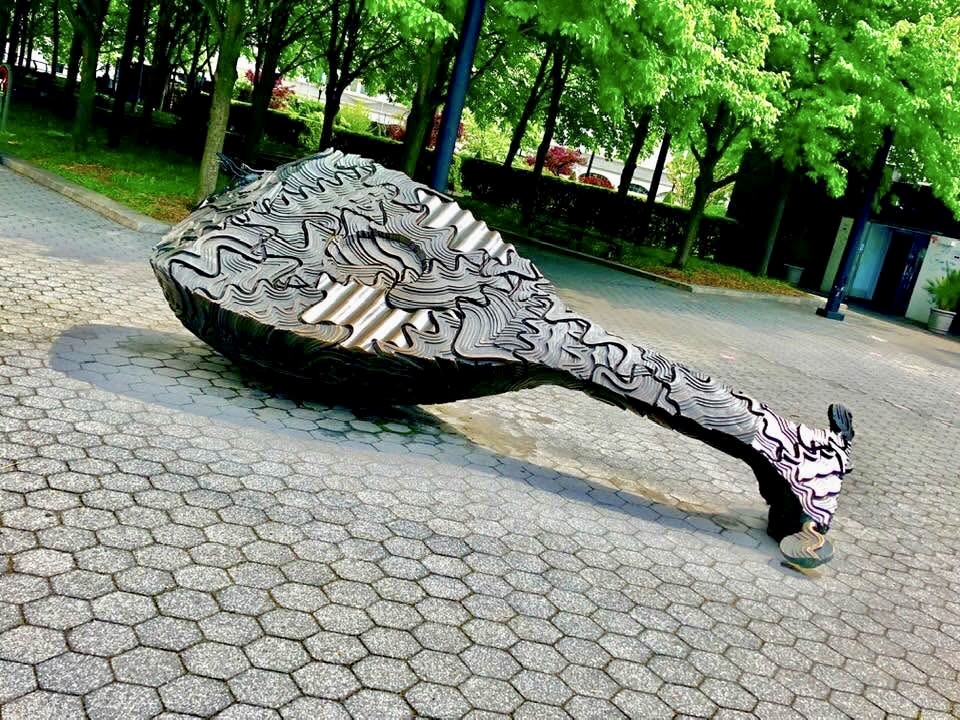 Giant sculpted ukulele lying across a paved plaza in New York